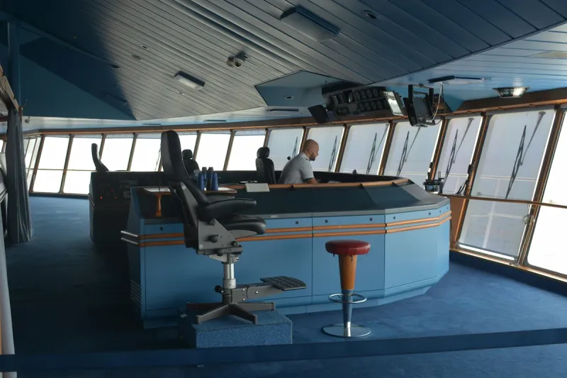 Ship bridge with officer at navigation console monitoring systems