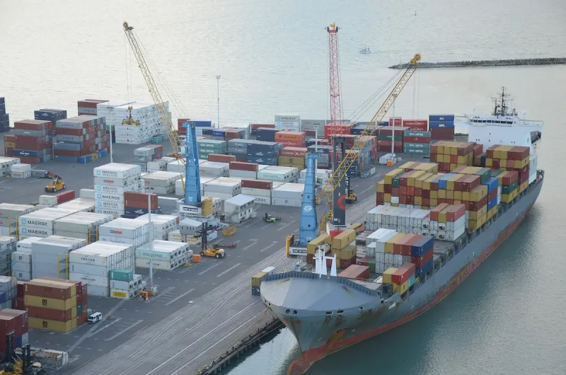 Aerial view of container terminal with ship alongside, cranes operating, and containers in yard
