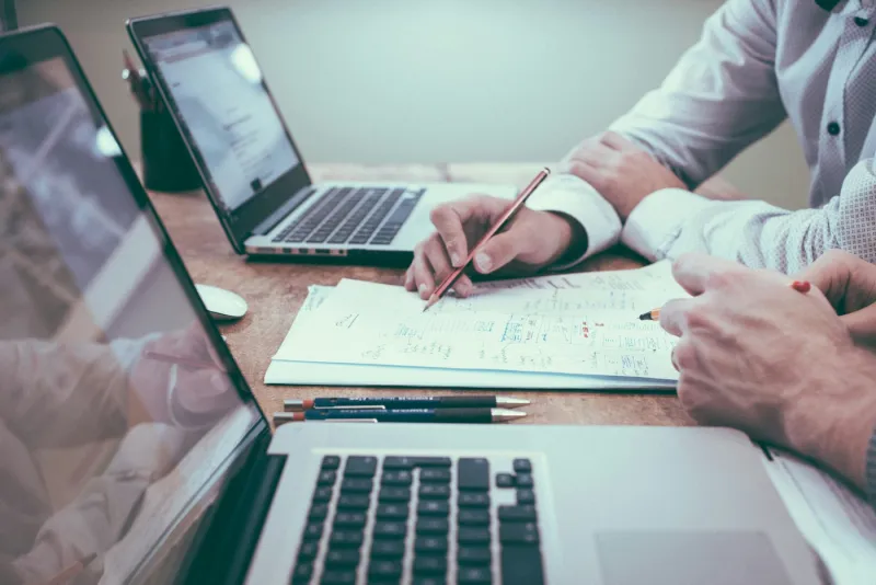 Professionals reviewing planning documents and diagrams with laptops on desk
